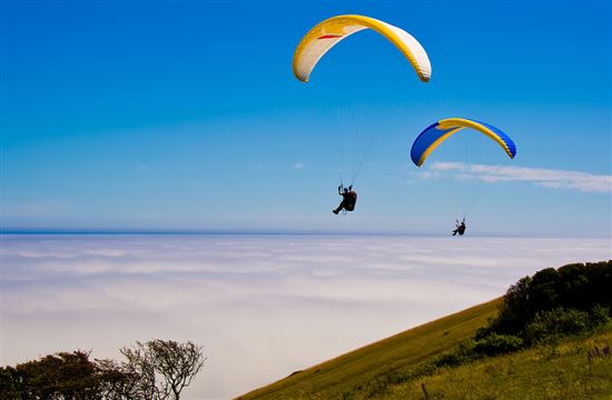 Two Hang gliders over beachy head sussex england showing a sea mist